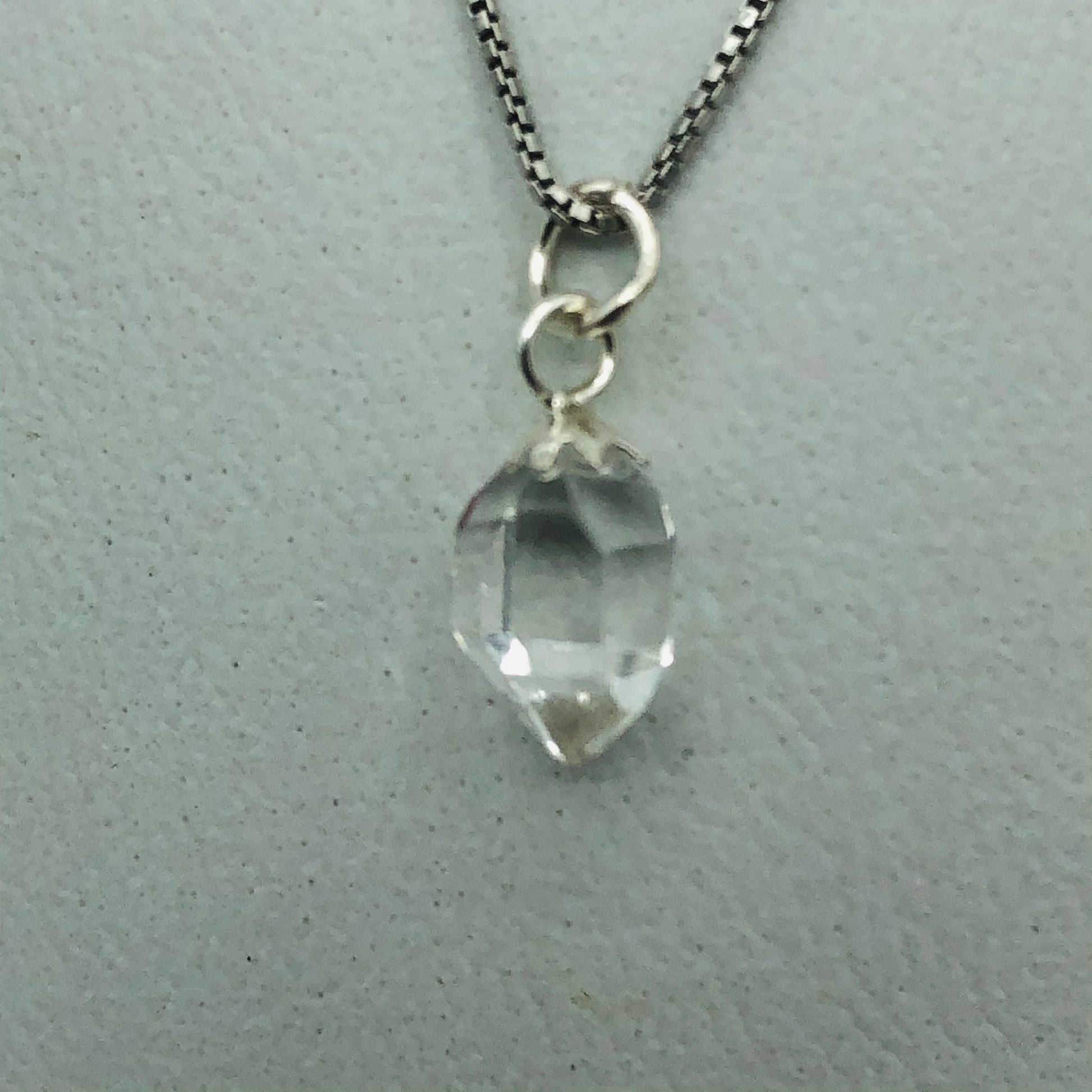 Herkimer Diamond Rhodium Plated Sterling Silver Box Chain on a jewelry pillow. (The Jewelry pillow is intended to be a prop and is not included in the purchase of the necklace. )